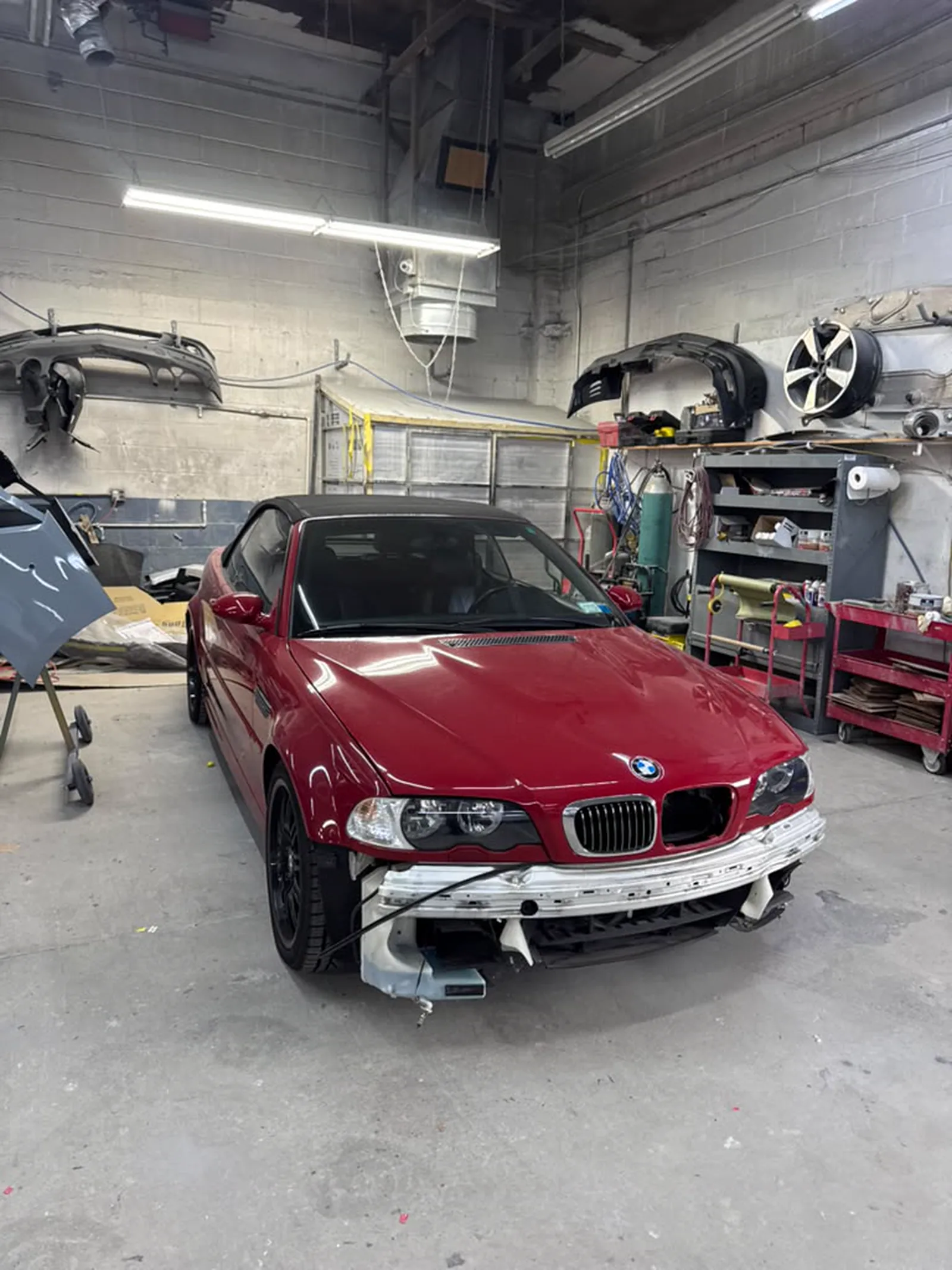 Red BMW M3 convertible mid-repair inside the bay