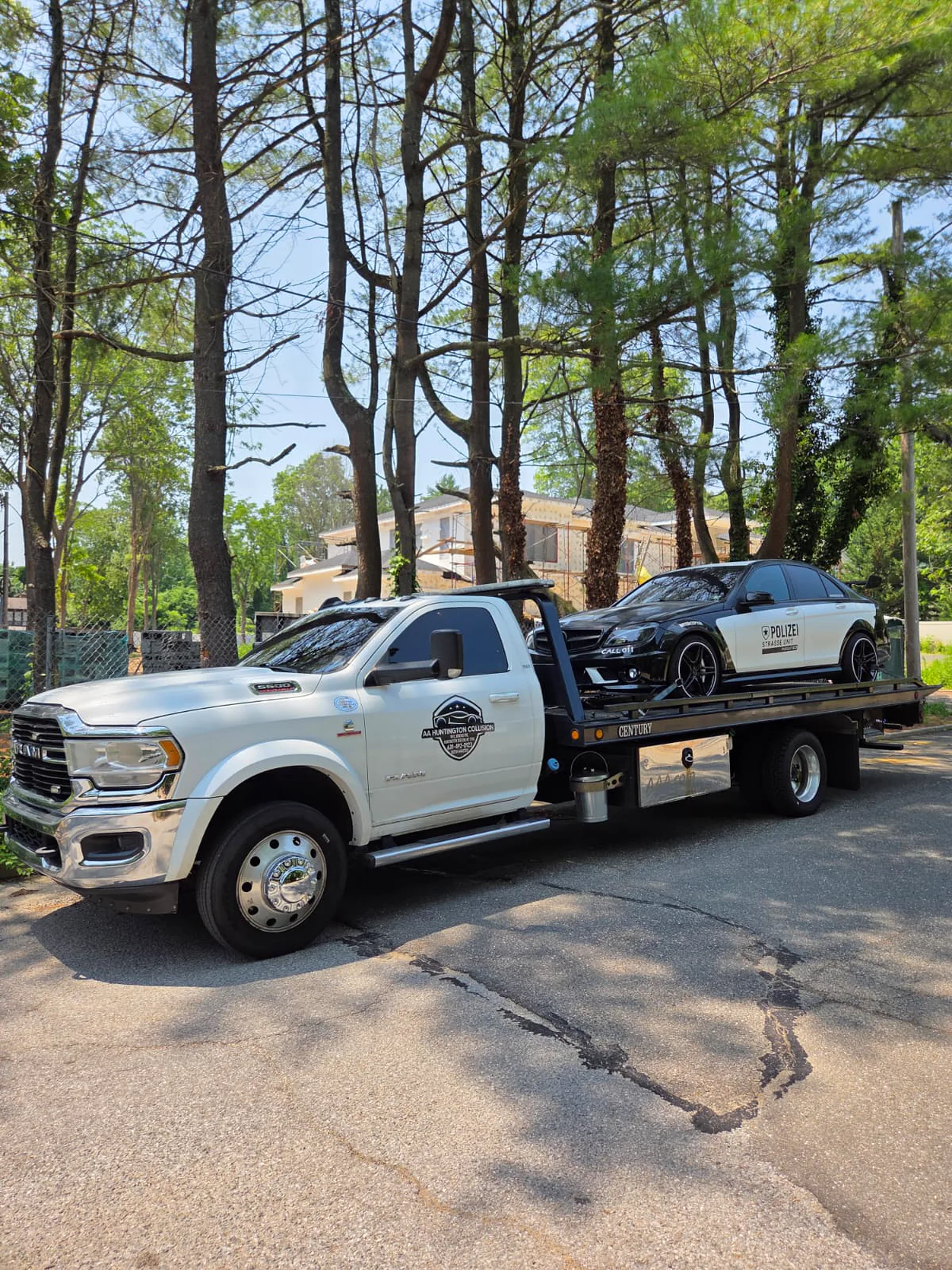 Flatbed tow truck collecting a Mercedes on a residential street